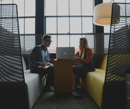 twee mensen die samen aan een laptop werken in een moderne werkruimte